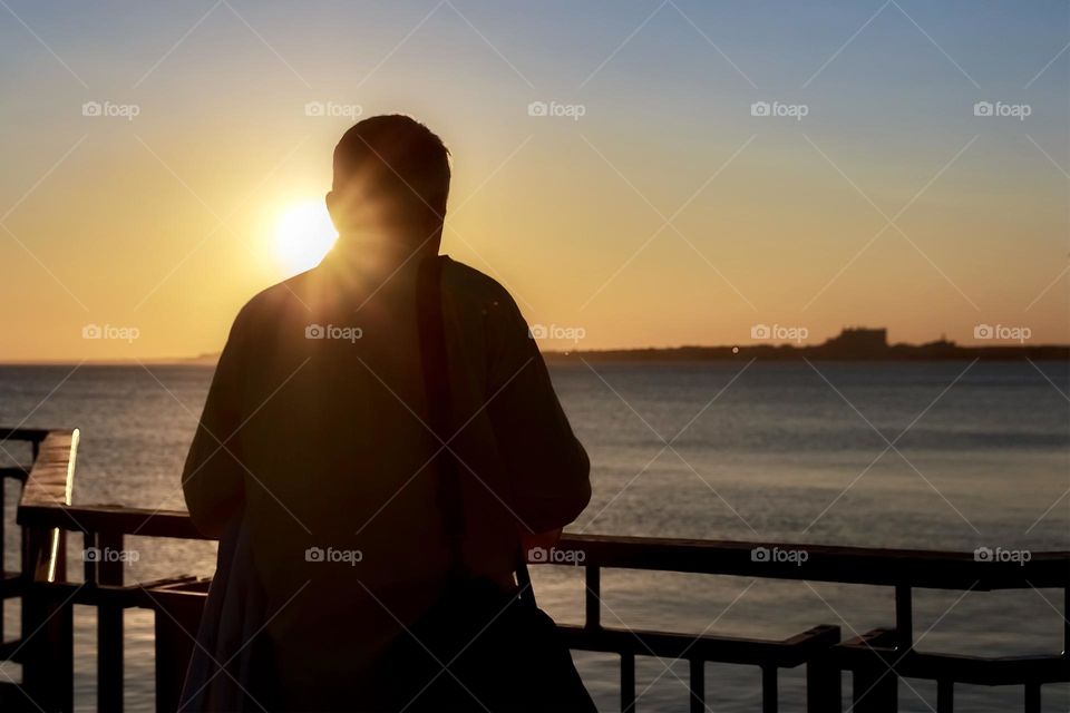 Back view of man and beautiful sunset over the sea