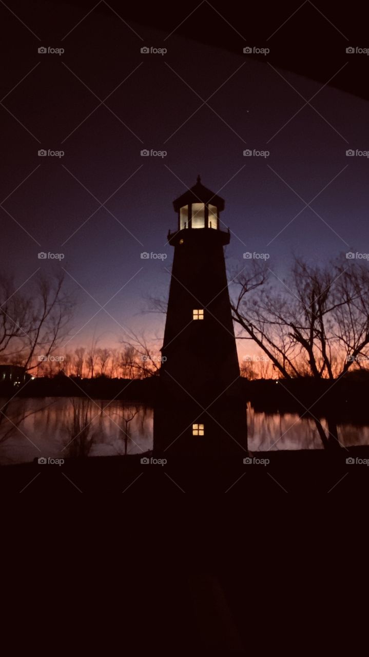 Lighthouse lit-up for the Evening. Twilight turning over to Night to End a Great Clear Cold Windy Day. Back lit Horizon showing its colors fading into Night.