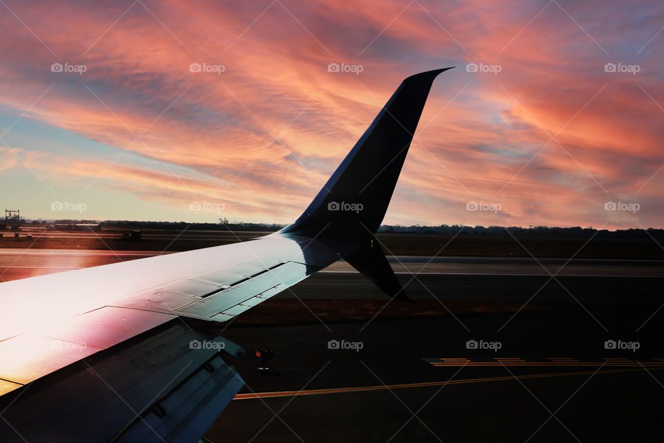 A beautiful sunrise is scene from the wing of a commercial airliner in take off from JFK Airport.