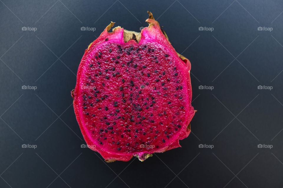 Close-up of a purple dragon fruit cut in half against a black background