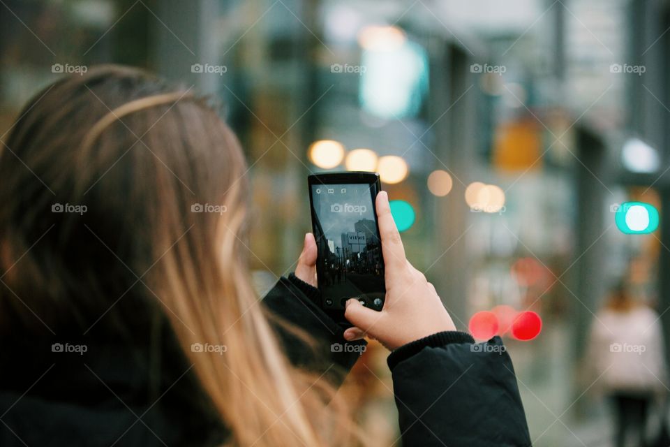 A young woman taking city pictures on her phone