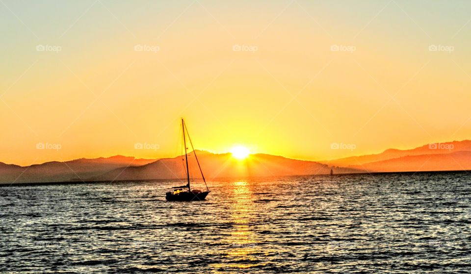 enjoying an evening at the marina and San Francisco California watching the sunset over the mountains as a sailboat sails by