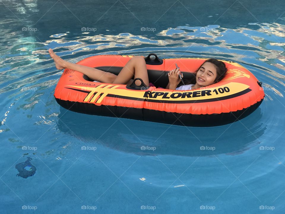 Ashley in her single blowup boat, on our pool.