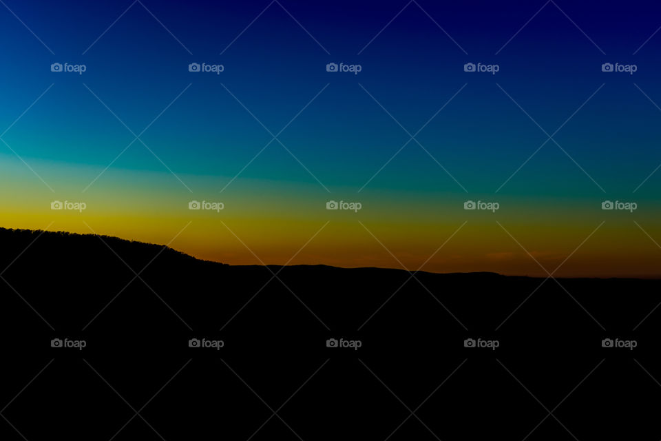 Sunset view by the mountains at late at night with a colorful sky and a mountain silhouette