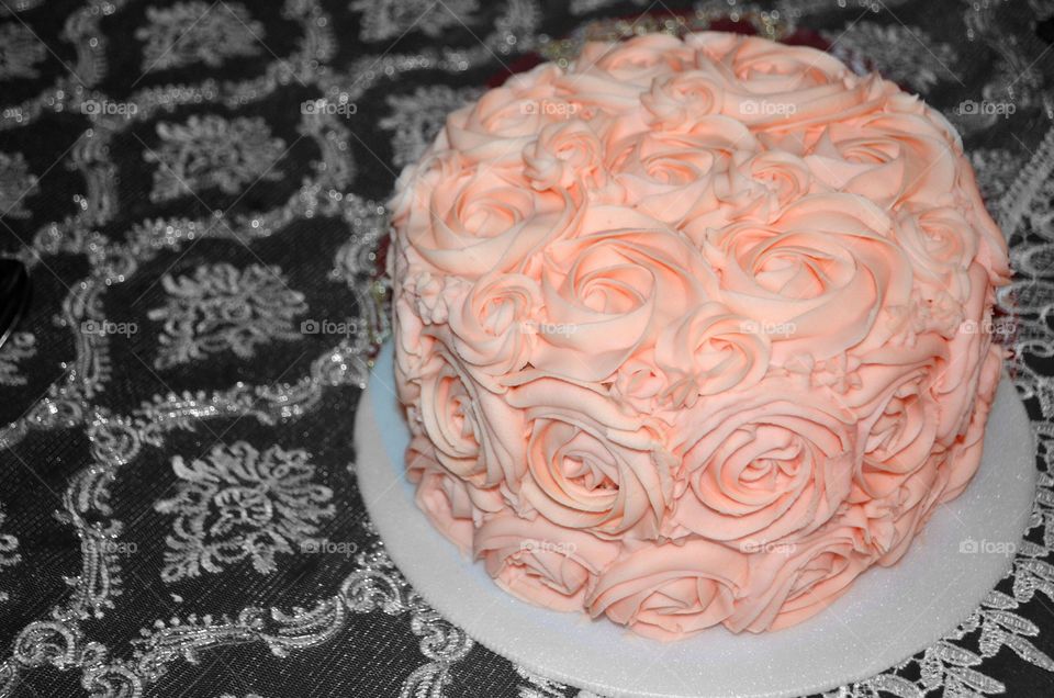 Wedding or birthday cake topped with fluffy raspberry meringue of edible flowers, pretty-in-pink velvet cake