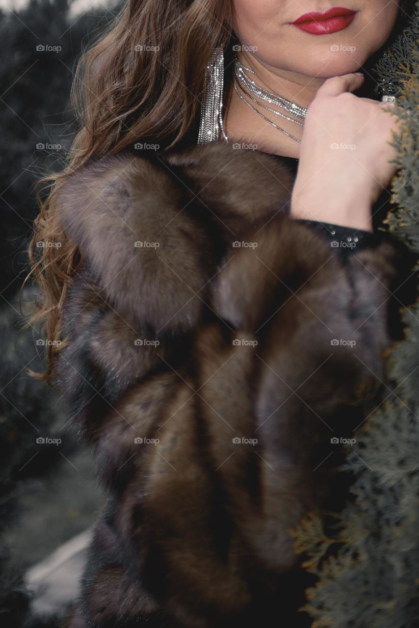 A girl in beautiful jewelry, in an evening dress and in a fur coat.