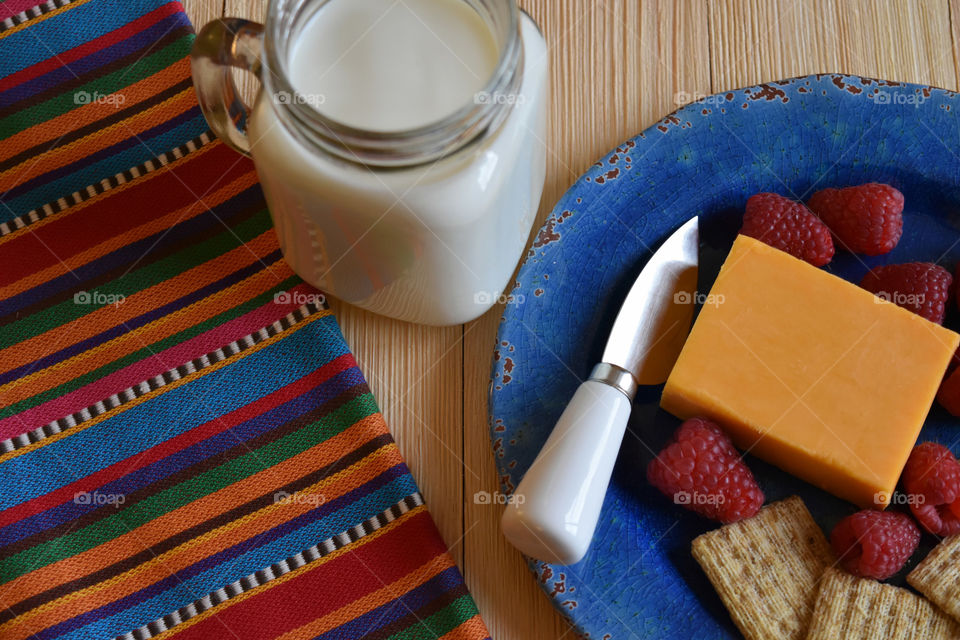 Cold glass of milk with plate of fruit and cheese