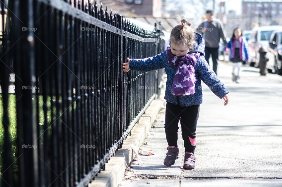 Cute girl walking on sidewalk in city