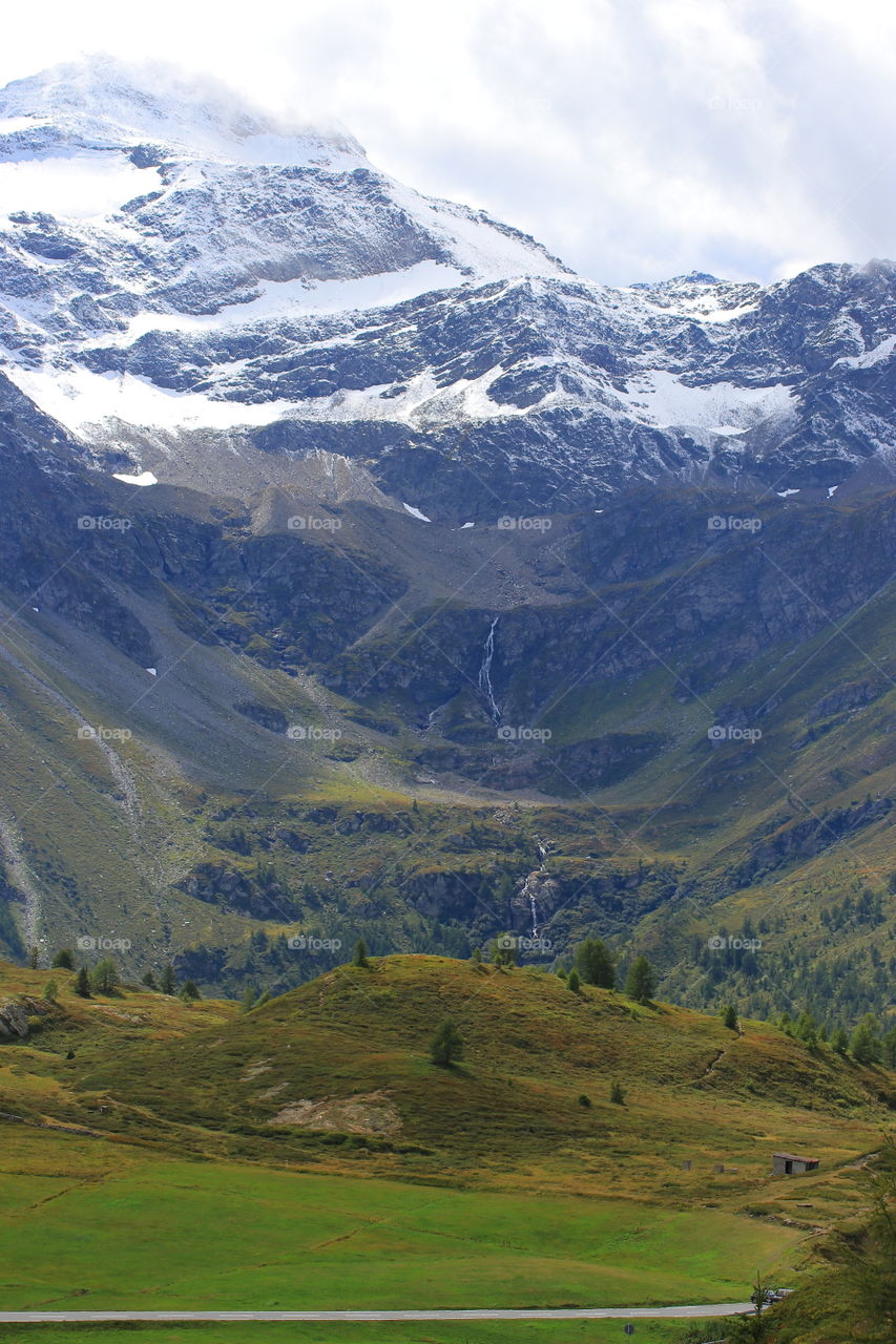 Beautiful waterfall in the Alpine snow-capped mountains with beautiful green meadows