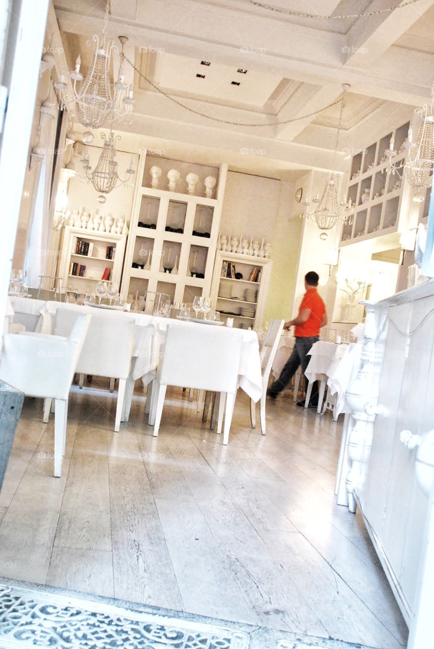 Study in white. A single red-shirted sever at An ultramodern restaurant prepares for the dinner crowd 