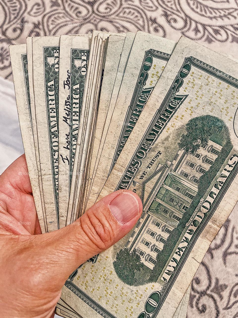 Woman’s hand holding money, United States paper bill currency, I Love Melissa Jones written on dollar bill, hand holding money, paying with cash