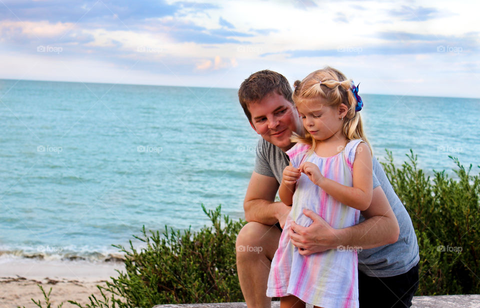 Father and daughter standing in front sea