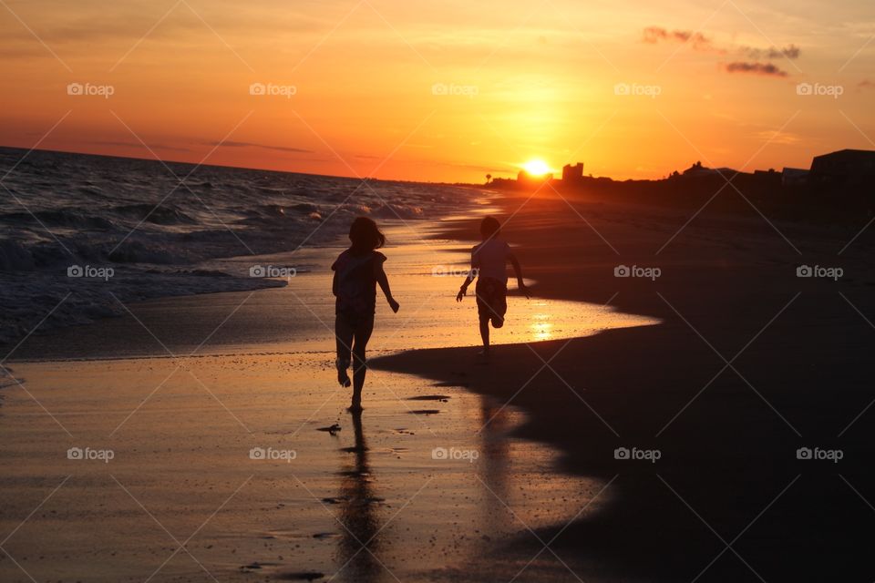 Silhouette of two child at beach during sunset