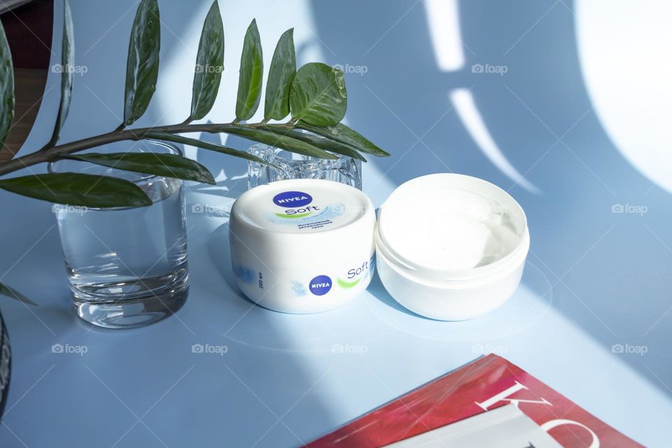 Nivea skin care product on a blue background with a green flower.