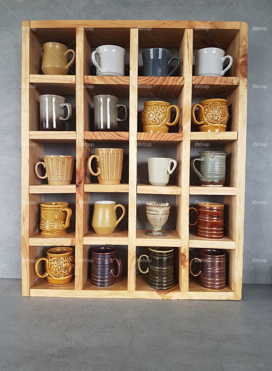 Wooden rustic shelf with ceramic mugs and pottery collection