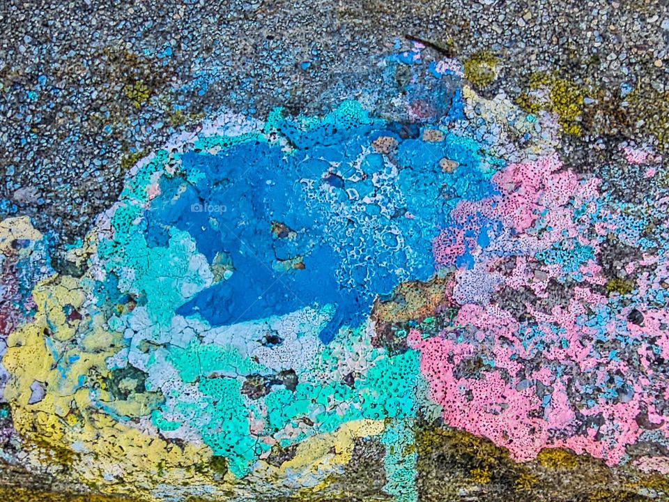 Paint splat on the sidewalk in San Francisco California with the colors of spring slowly degrading as people walk over it, pastel colors of blues, greens, pinks, yellow, turquoise, 