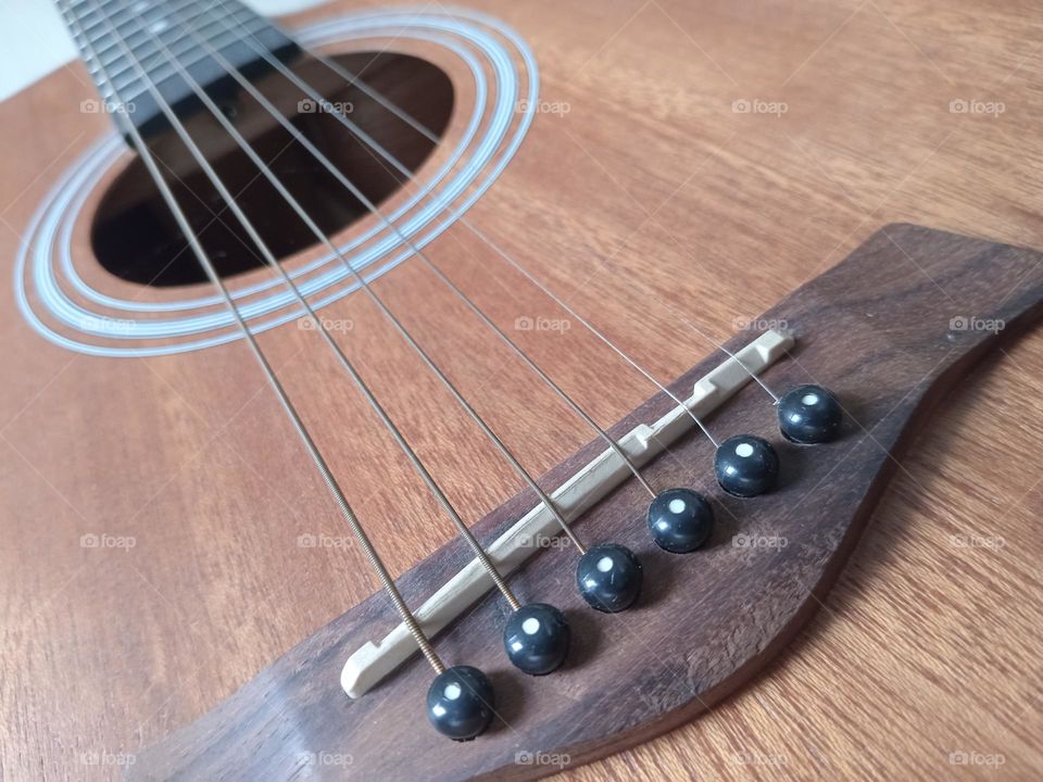 An acoustic guitar is a type of guitar where the sound produced comes from the vibration of the guitar strings that are channeled through the saddle and bridge where the strings are attached into the sound chamber