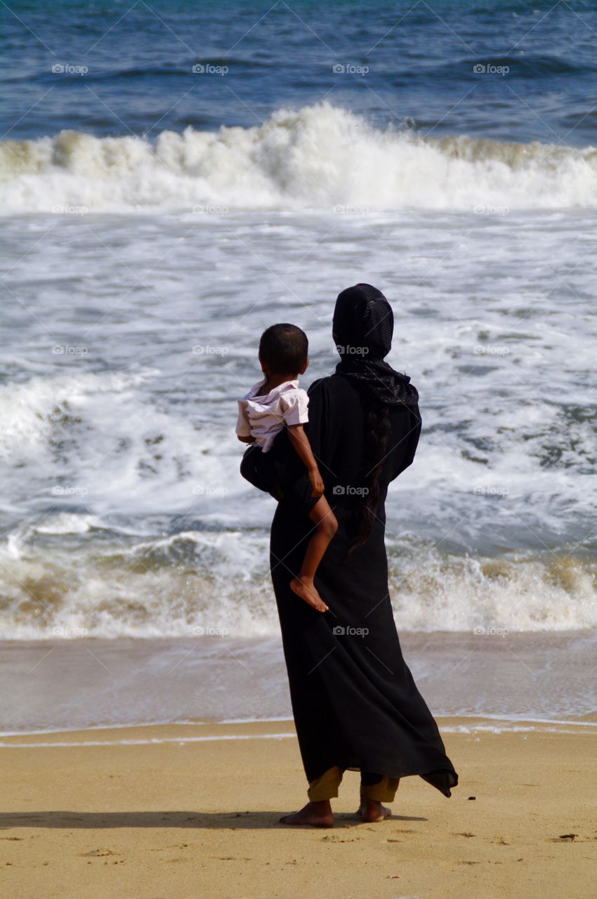 Muslim woman on the beach . I saw this woman in chennai on marina beach. India. She was standing with her son, and looking on the ocean.