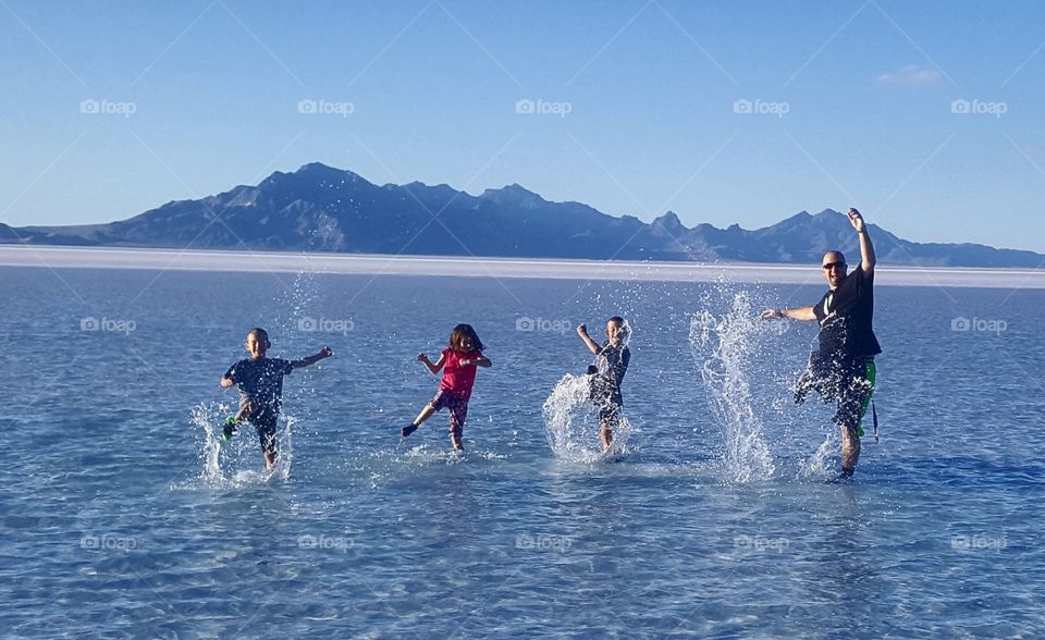 Family Fun splashing in the water with mountains rising in the background at the Great Salt Lake near Salt Lake City Utah United States of America 2017.