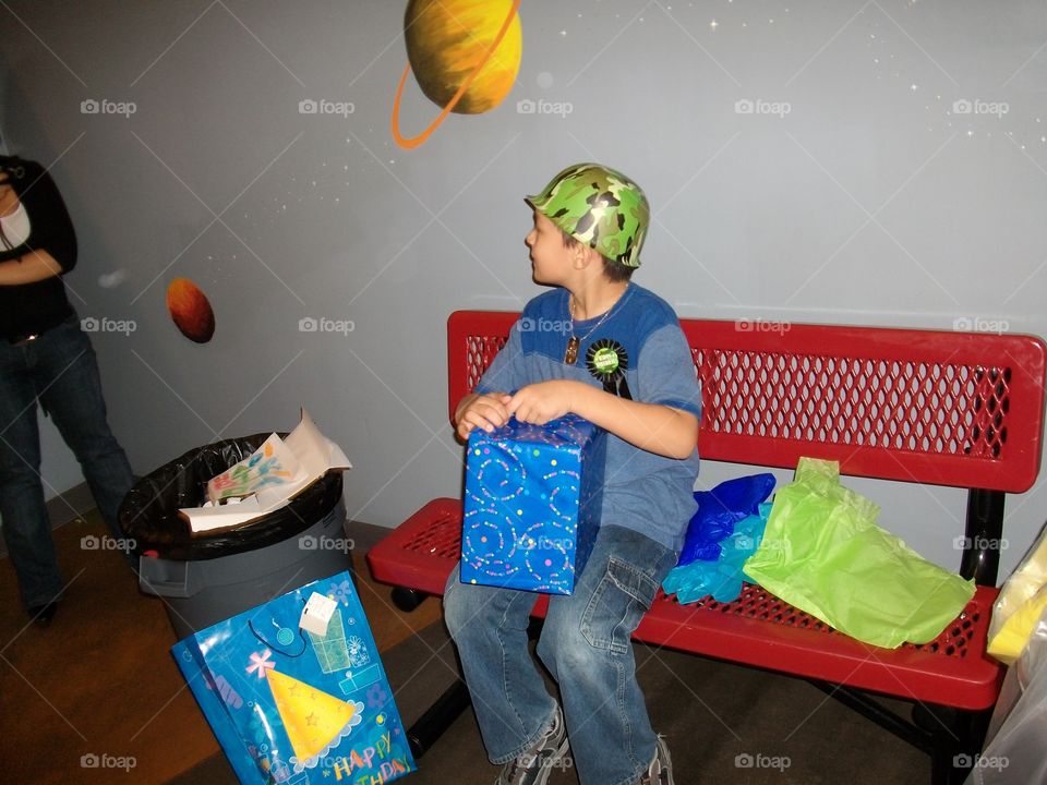 Boy sitting on bench with gift box in hand