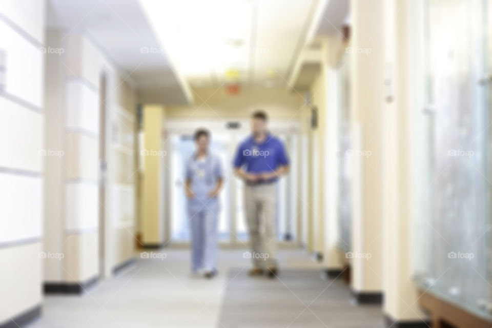 Blurred out hospital hallway with two caregivers walking 