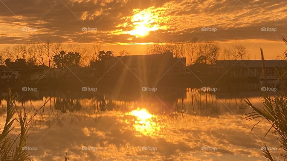 Sunbeam shine down to surface of Lake Waters beam splits and shines in different directions. All in the evening of a sunset in a special evening. Reflections of the sun beams On lake waters reflecting back to the clouds and the shoreline. Beautiful.