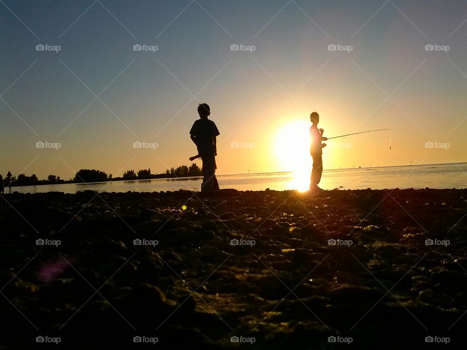 Silhouette of two children's fishing in sea