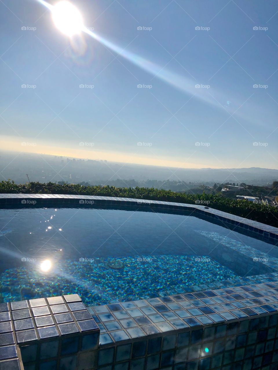 Beautiful sunny day with a stunning view of Hollywood Hills and Los Angeles. Top deck luxury pool to enjoy the mountain and city views. 
