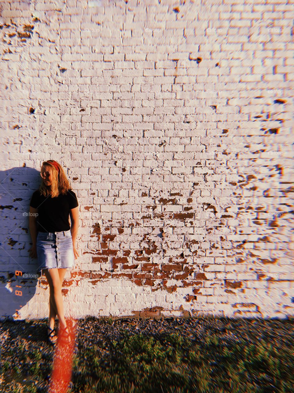 Girl leaning against a brick wall during summer sunset. 