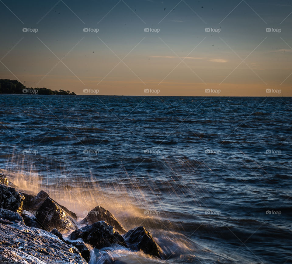 Sunrise splashing waves on rocks. Waves splashing onto rocky shore at sunrise