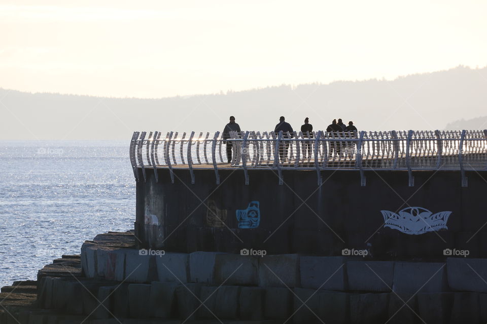 Silhouettes of people on the breakwater 