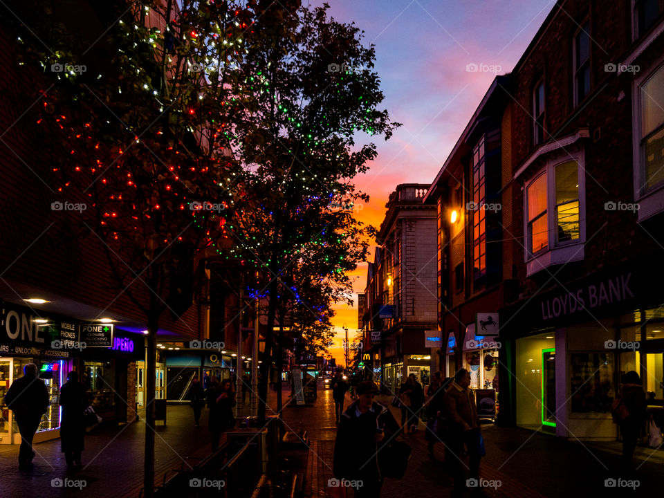 Urban Sunset: a beautiful sunset framed by a tree lined shopping street with people in silhouette. 