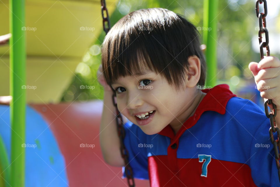 Happy smiling kid on the swing. Thithi enjoy spring