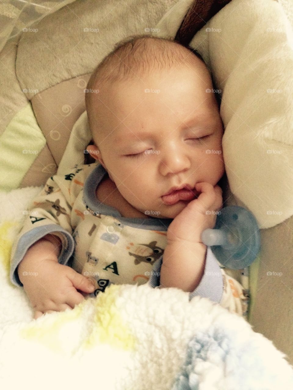 Adorable boy sleeping with soother on bed