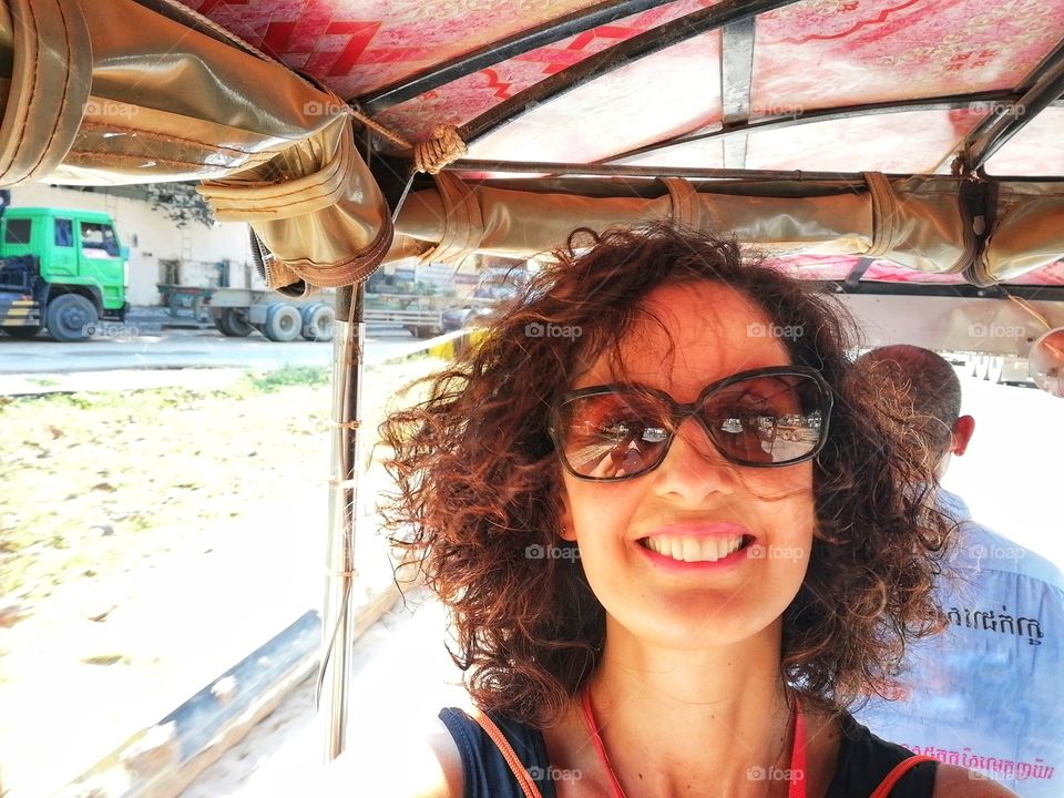 smiling woman on a three-wheeler on the Cambodian streets with friends