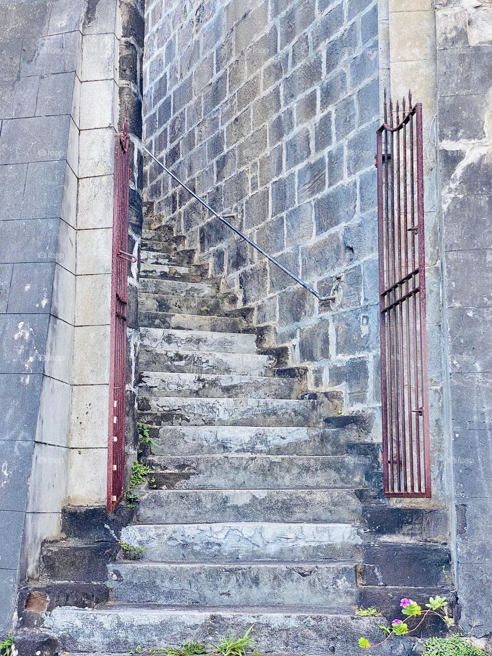 A curving staircase with a metal gate at the bottom in an old fort