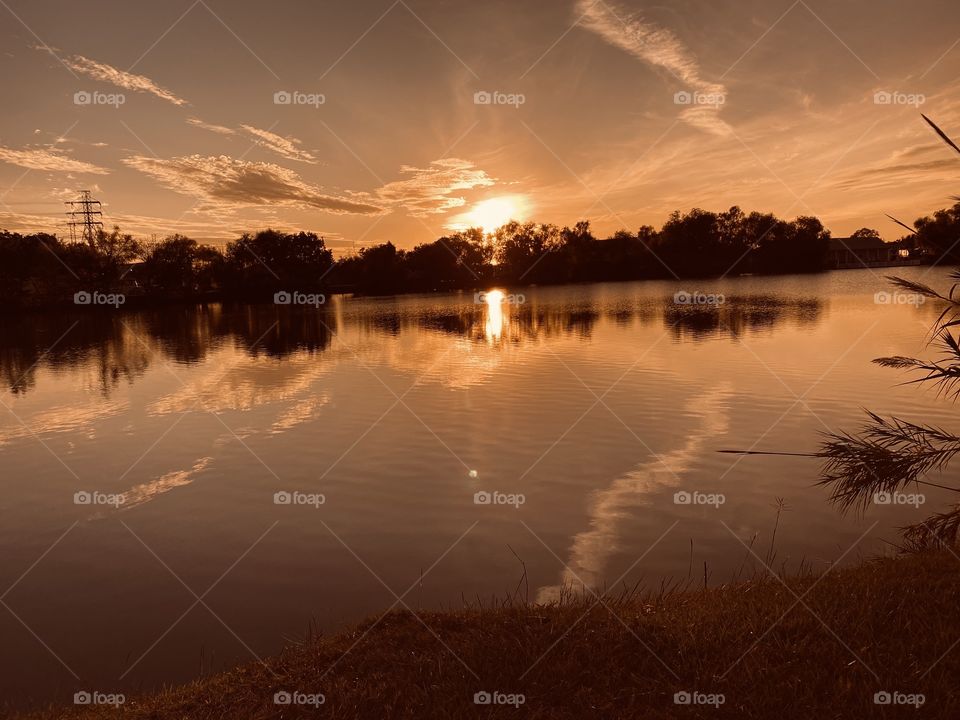Sunset gleaming Sun’s Ray interrupted by high clouds casting Mirrored images on the lake water from all around the sky. 
