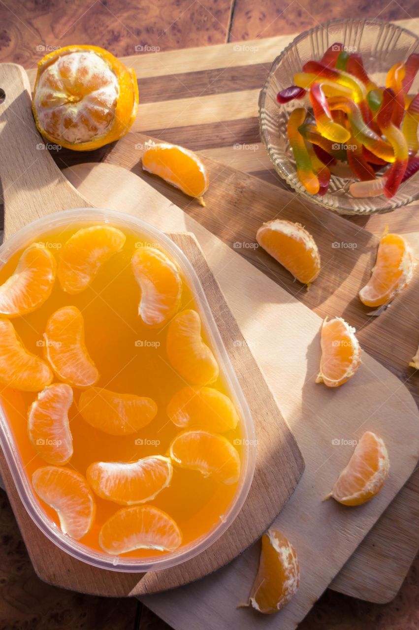Delicious orange jelly with tangerine slices in a container and jelly worms.