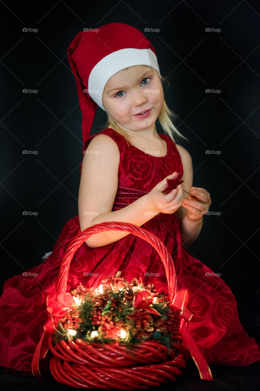 Four year old girl posing in santa dress for christmas.
