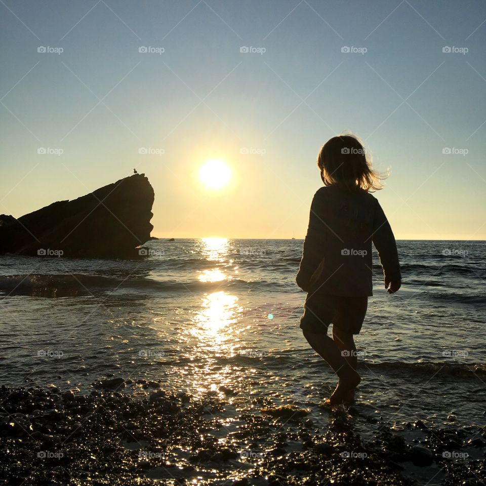 Silhouette of a young boy on a sunset blessed beach in North Devon. Childhood is about experiences, what he sees, feels and learns. 