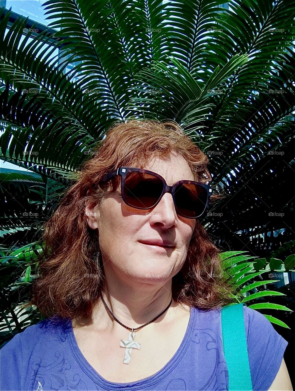 In the warm glow of the afternoon sun it comes natural to be photographed against a backdrop of exotic plants such as these voluminous palm trees at the botanical garden of “Berlin”, Germany in the “Steglitz” district. 2024. Hypnotic Productions