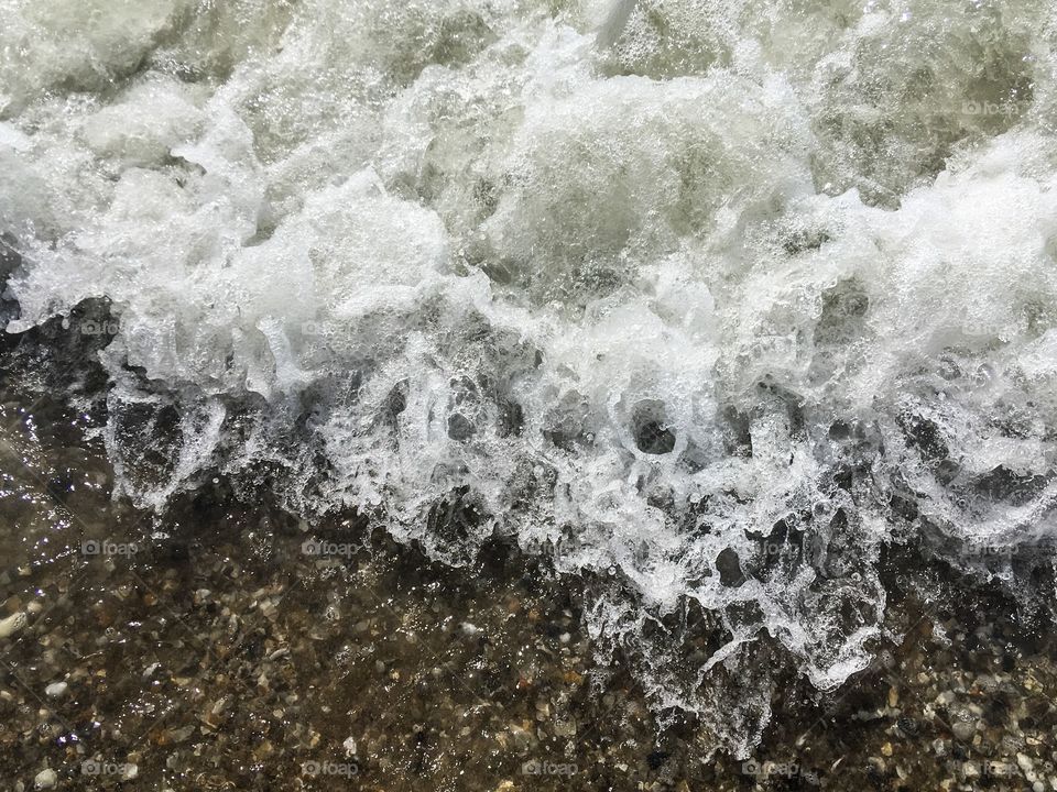The seaside. Sand and wave. The tide. The Black Sea. Summer beach. Summer time. The sea ​​foam background and texture. 