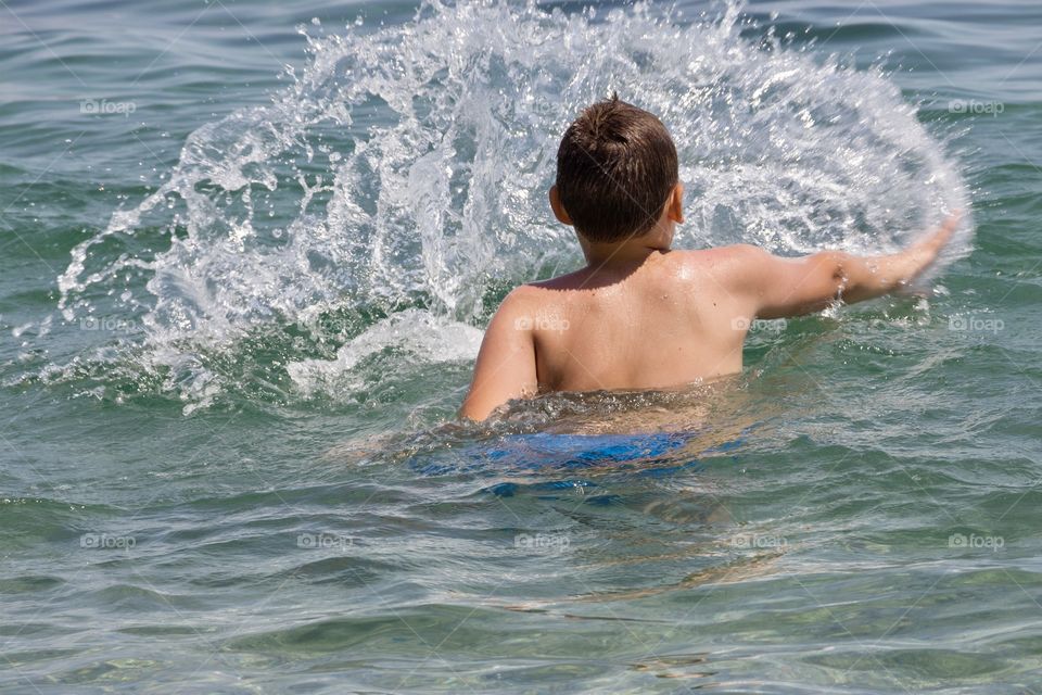 Boy playing with the water in the sea
