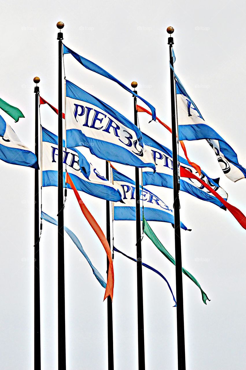 Circular round tops of flagpoles as flag blow in the wind