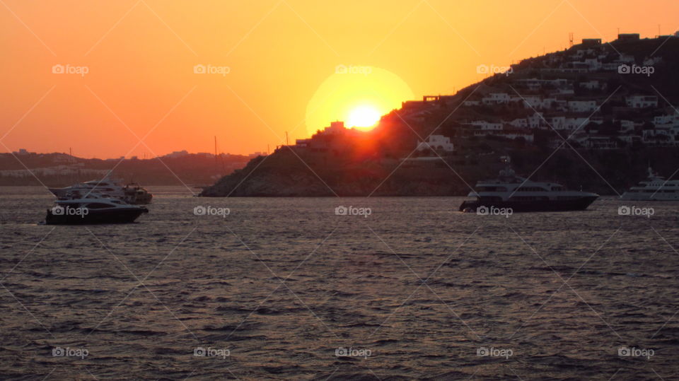 Greek islands sundown Mykonos. Watch the sunset ritual at Scorpios beach  Paraga, Mykonos island Cyclades Greece.