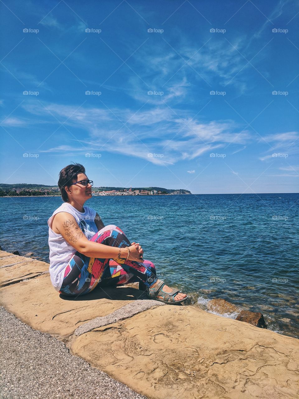 Young woman dreaming and sitting close to the sea beach