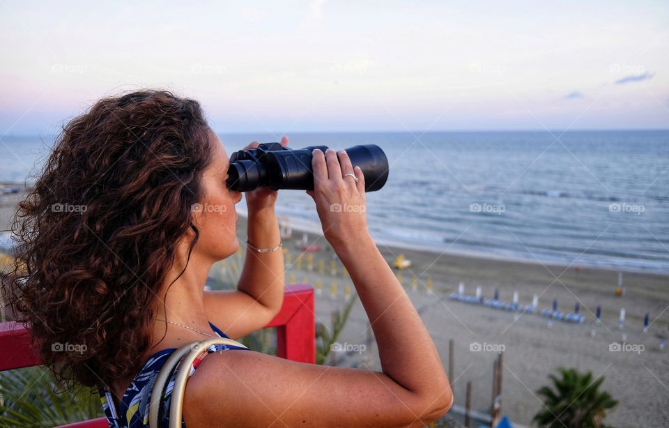 Woman looks at the horizon with spyglass