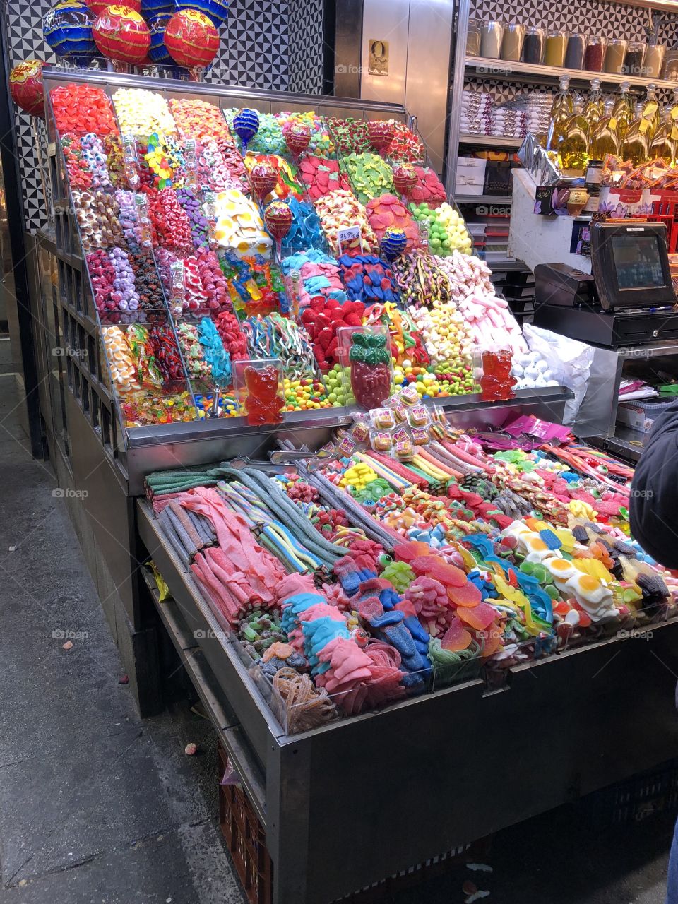 A colorful, inviting sweet candy stand in a bustling central market in a European city.