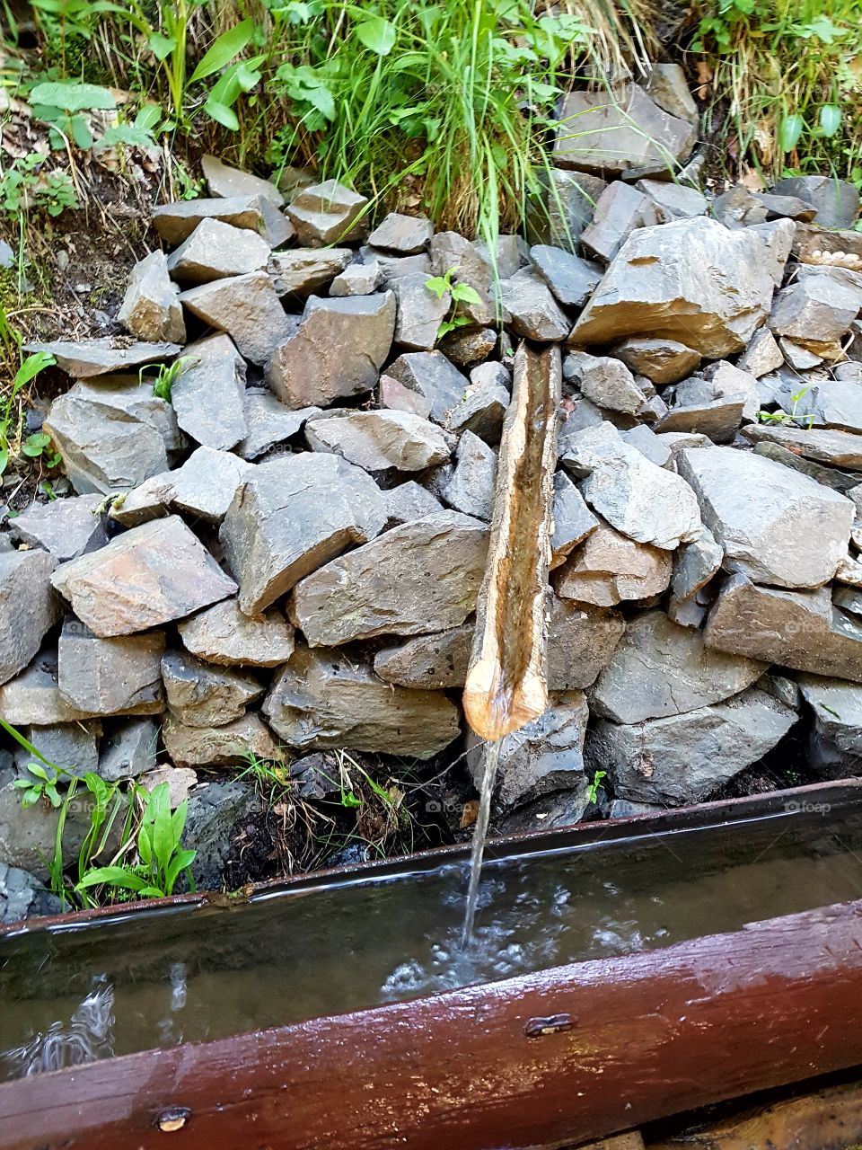natural fountain between stones and wood