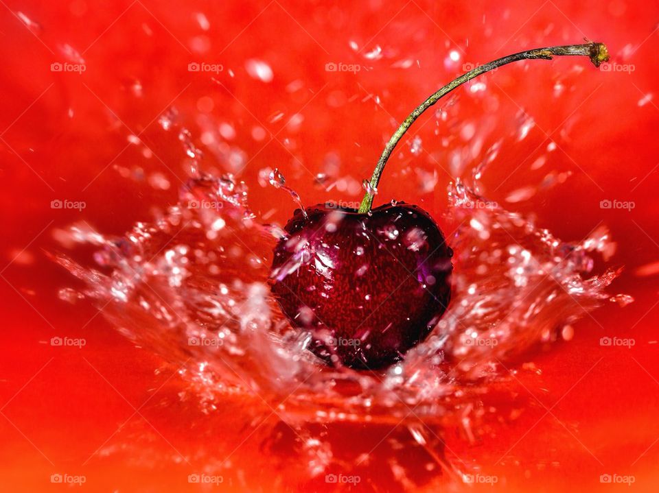 Cherry in water splash over red background